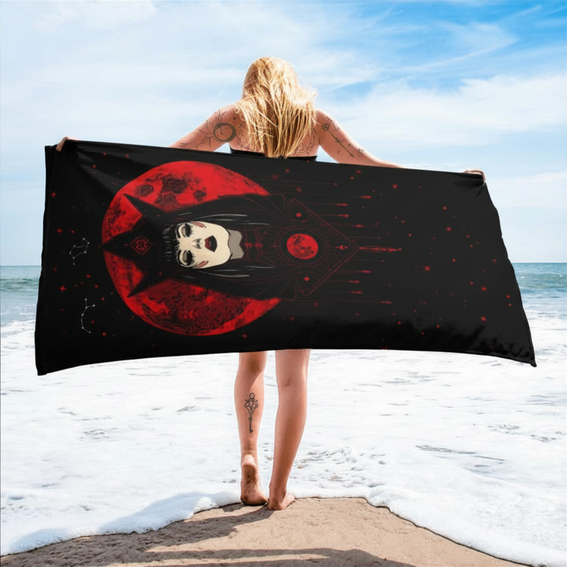 Person holding a black and red towel with a woman design on a beach