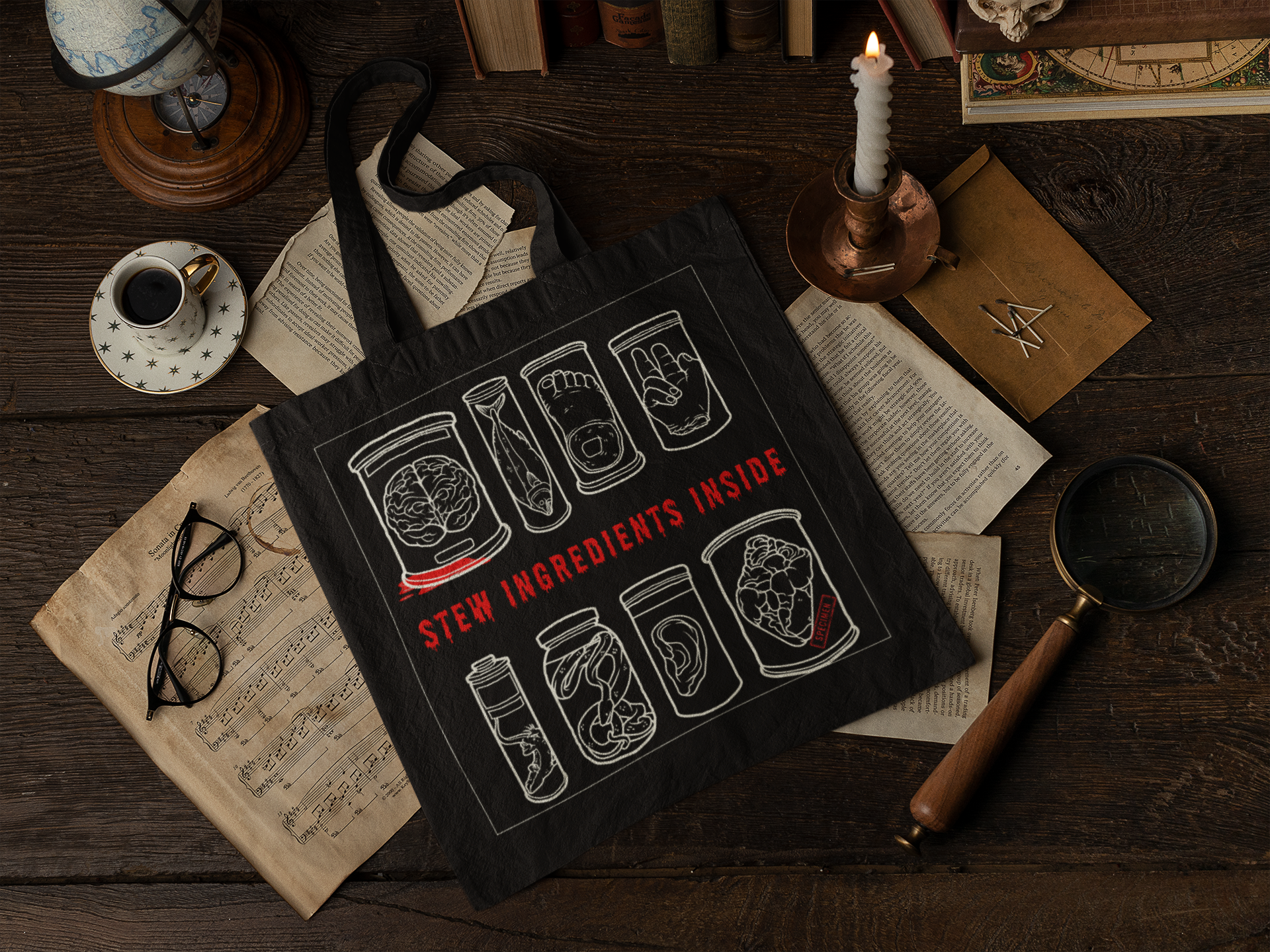 Black tote bag with potion jar design on a wooden surface with books and a candle.