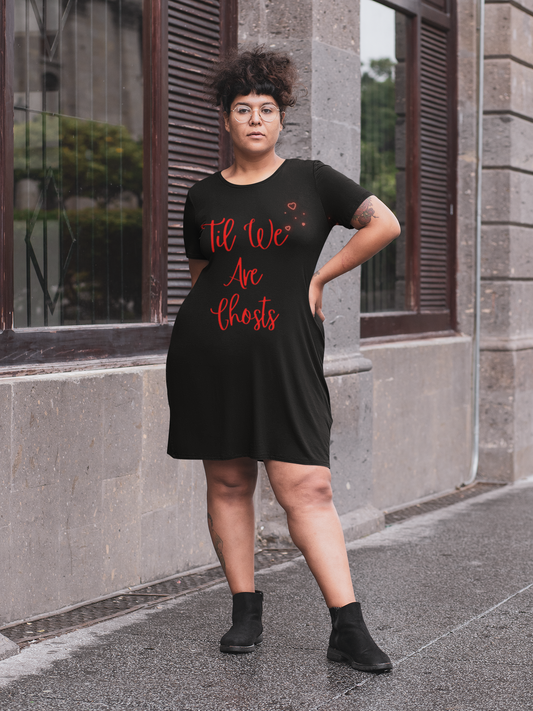 Person wearing a black t-shirt with red text saying til we are ghosts standing on a street.