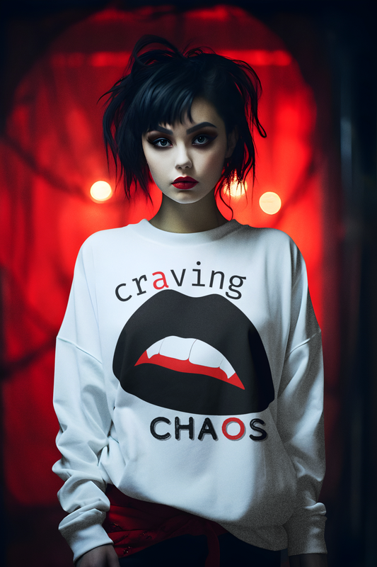 Person wearing a white sweatshirt with vampire lips that says 'craving chaos', standing against a red background.